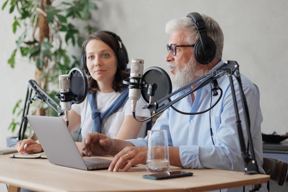 a European adult man with gray hair and a young woman in a recording studio create audio content