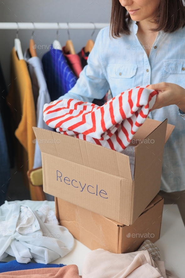  woman puts clothes in a box for recycling. garbage sorting and eco friendly lifestyle