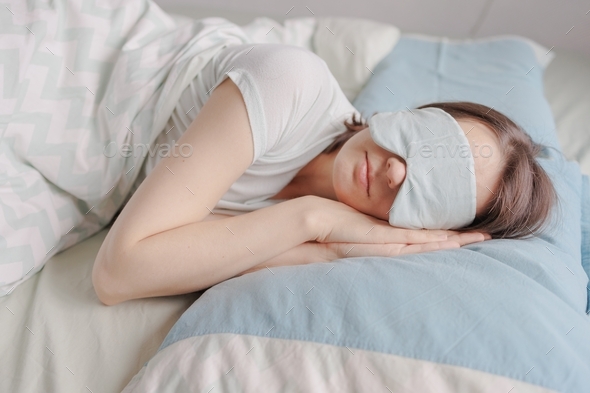 woman with dark hair in bed with a mask over her eyes cannot fall asleep or is sleeping