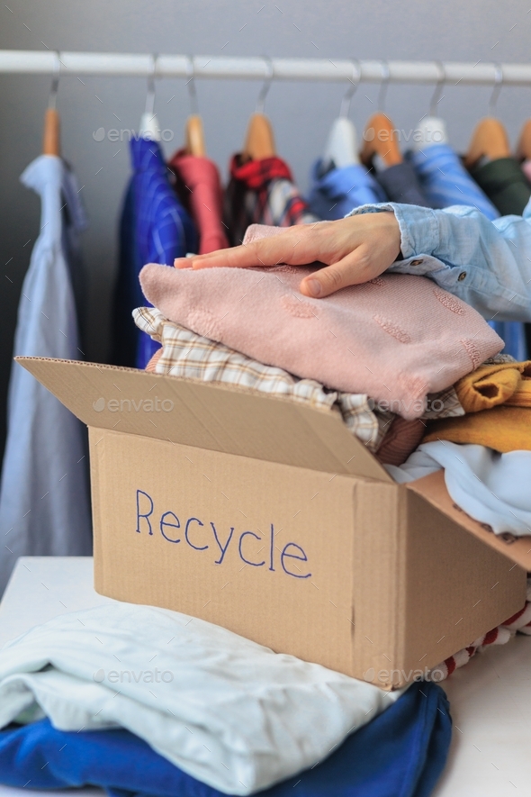 a woman\'s hand on a box of clothes for recycling, environmentally friendly lifestyle