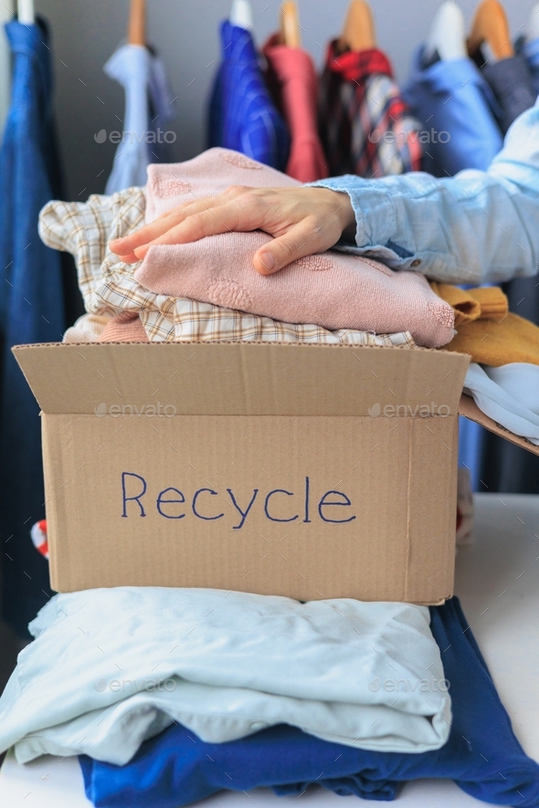 woman puts clothes in a recycling box. garbage sorting and an