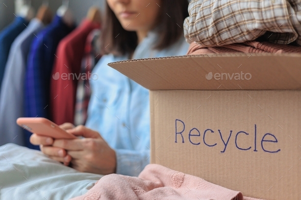 woman puts clothes in a recycling box. garbage sorting and an environmentally friendly lifestyle