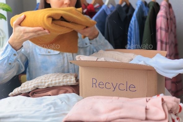 woman puts clothes in a recycling box. garbage sorting and an environmentally friendly lifestyle