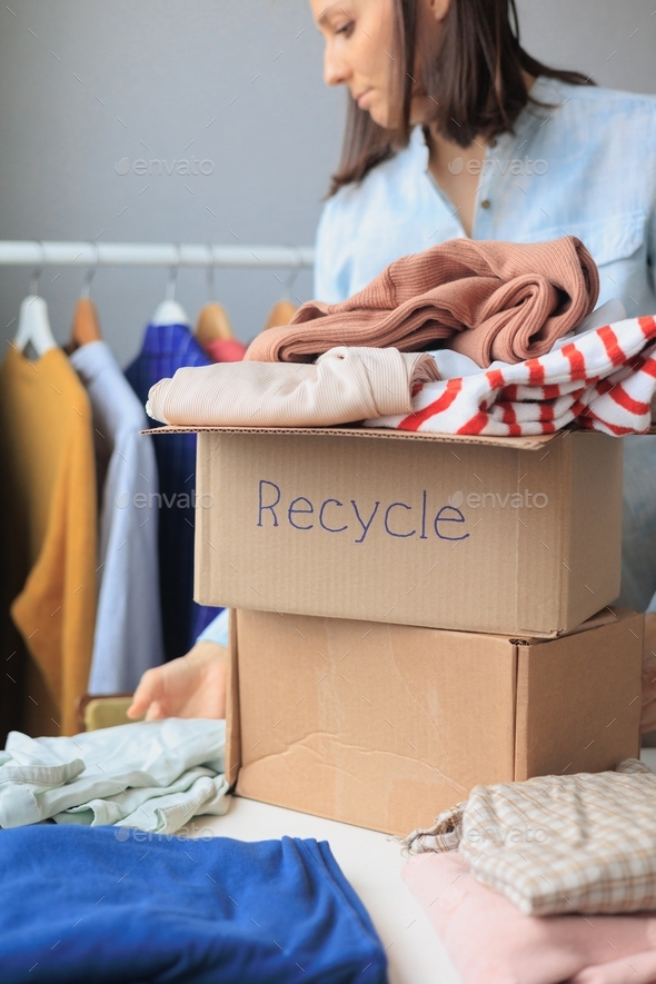 woman puts clothes in a recycling box. garbage sorting and an