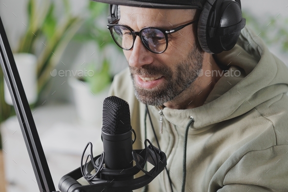 records audio content or podcast for his blog. a serious adult European man in a baseball cap