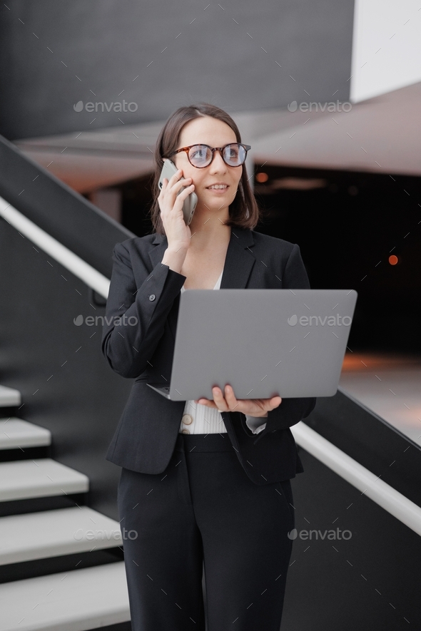  woman in an office or a congress center climbs the stairs and holds a laptop in her hands