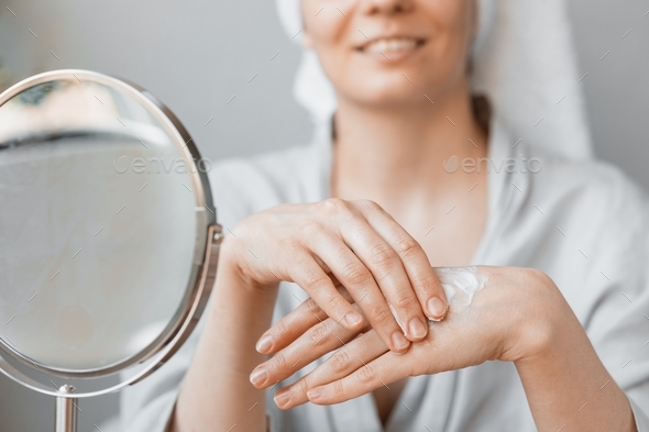 Caucasian woman at home or in the spa applies hand cream or body balm, moisturizing hand and body