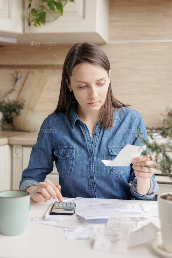 woman sits at the kitchen table, pays utility bills and writes checks.the calculation of social