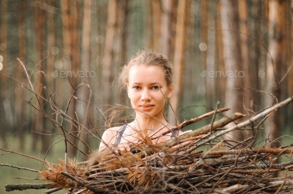 teenage girl survivalist collect branches firewood for a campfire nature traveling. local travel