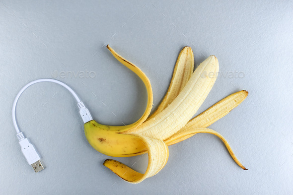 A fresh ripe banana connecting with a usb charge cable. Color of the year 2021.