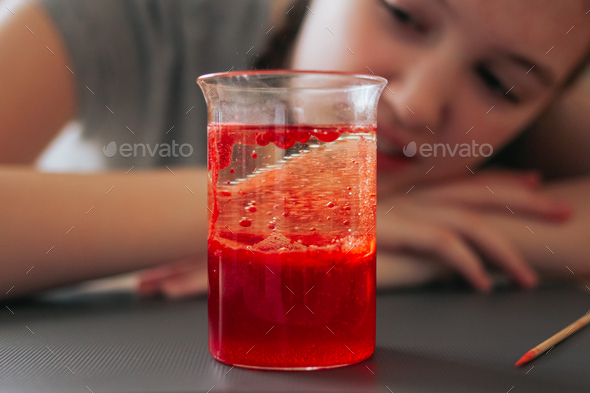 School girl doing science experiment with water, food coloring, oil and aspirin. Education. N
