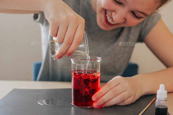 School girl doing science experiment with water, food coloring, oil and aspirin. Education. N