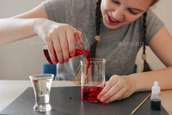 School girl doing science experiment with water, food coloring, oil and aspirin. Education. N