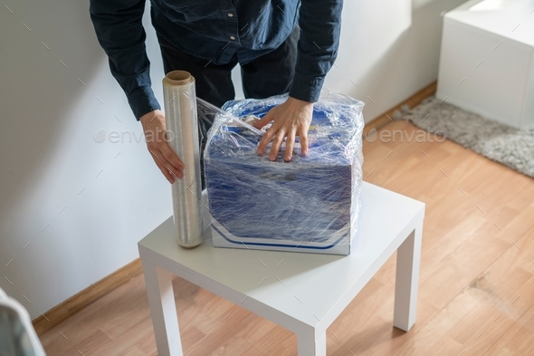 a person wrapping the package with plastic protective stretch wrap
