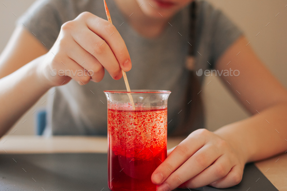 School girl doing science experiment with water, food coloring, oil and aspirin. Education. N