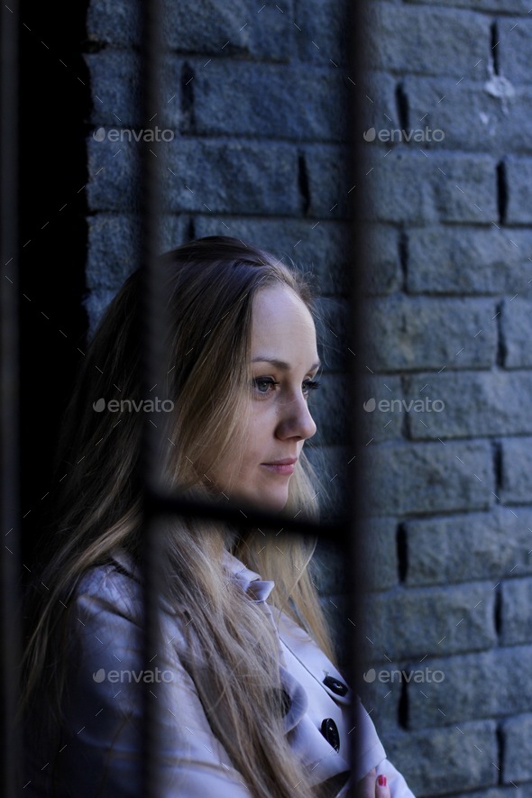 beautiful woman in a trench coat leaning on the loft brick wall deep in ...