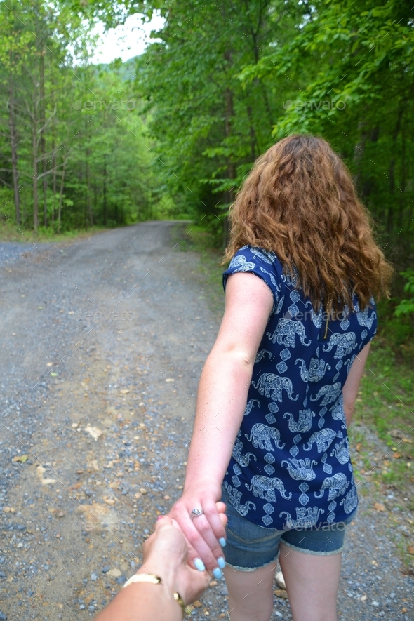A female (young woman) leading the way down a gravel lane in the woods - follow me