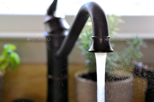 Kitchen Sink Faucet with running, spraying water with a window and herbs herb plants - Stock Photo - Images