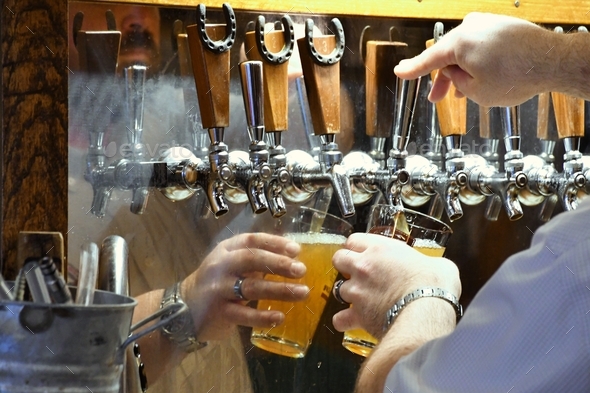 A man filling a glass with beer from a beer tap at a local brewery