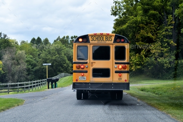 A yellow school bus stopped on a rural road to pick up and drop off students.