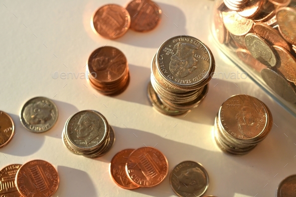 Stacks piles of spare change coins, pennies, dimes, nickels, quarters, loose change jar, saving