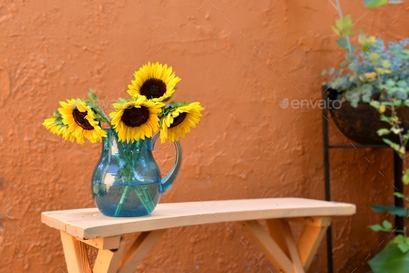 Mediterranean Courtyard - orange stucco walls with a bench, blue pitcher full of sunflowers.