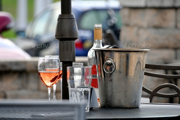 Enjoying wine on patio - two glasses of rose blush wine in glasses next to a bottle and wine bucket.