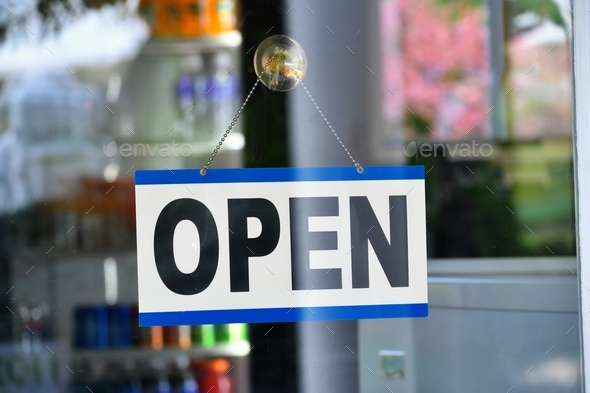 Open sign hanging on a shop\'s door window - Yes, we\'re open for business