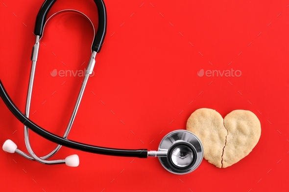 Heart attack concept - stethoscope on broken heart-shaped cookie on red, cardiac arrest heartbroken