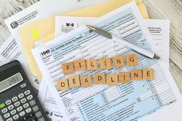 IRS tax forms 1040 words FILING DEADLINE in wooden tiles with calculator W2 W9 April 15 paperwork