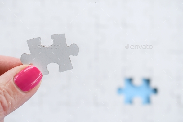 Female holding white puzzle piece with blue empty space in background, add your text copy, mock up