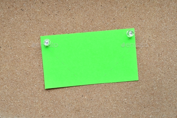 Blank green note card pinned with push pins on a corkboard bulletin board for mock up own message