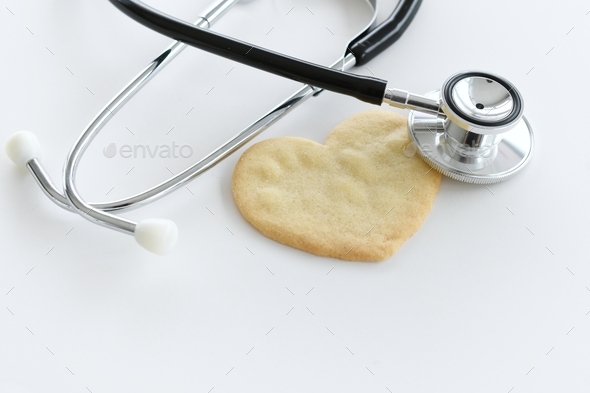 Heart health concept - stethoscope heart-shaped cookie on white, cardiac arrest, heart attack