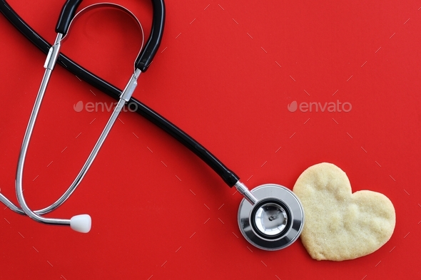Heart health concept - stethoscope heart-shaped cookie on red, cardiac arrest, heart attack