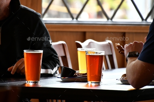 Men drinking beer at a brewery restaurant, glasses pints of beer or ale.