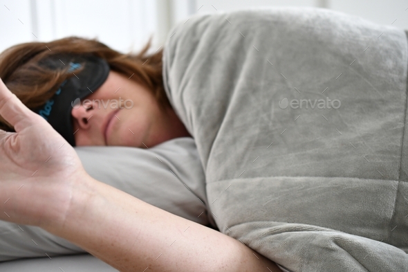 adult woman with a Do Not Disturb sleep mask on and her hand out to fend off being woken up. Go away