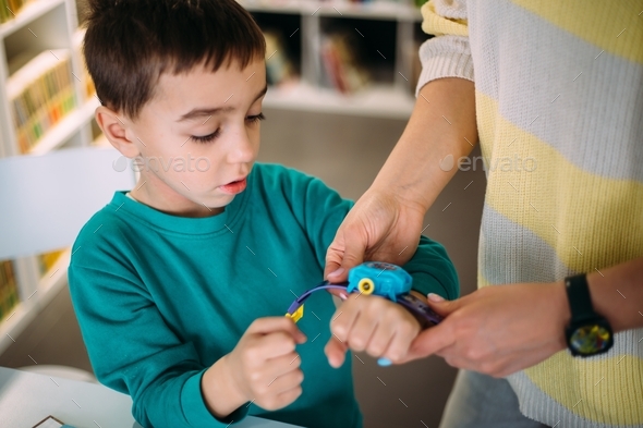 Mom gives her son a preschooler his first watch. Learning to determine the time by the clock.