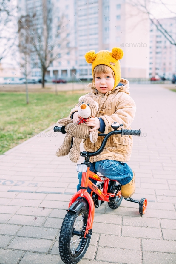 A small child learns to ride a bike for the first time in the city in spring.