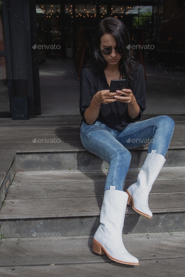 woman sitting on stairs and chatting to social media by cell phone
