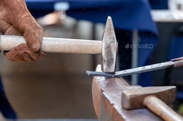 Unrecognizable blacksmith forging red-hot metal with hammer. Blacksmithing concept.
