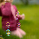 A little girl is sitting on the grass and blowing soap bubbles - PhotoDune Item for Sale
