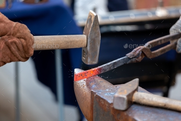 Shaping the metal. Unrecognised blacksmith forging red-hot metal with the hammer. Blacksmith concept