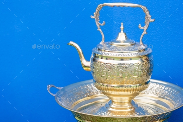 Traditional Moroccan tea pot against bright blue background with copy