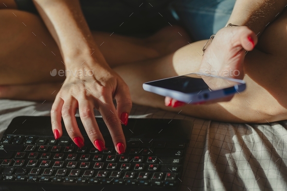 Young woman typing on laptop. Working at home, freelancer job concept, day light dynamic workplace.