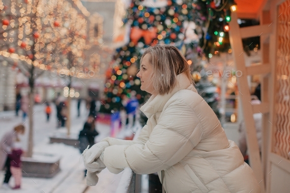 A young woman walks in the square during the Christmas holidays. Snow ideas