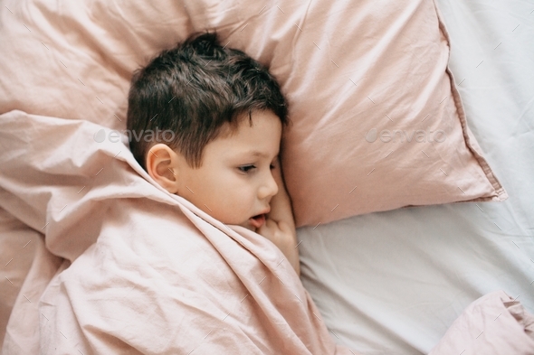 A 5-year-old boy sleeps on a large pillow covered with a blanket. Don’t want to wake up