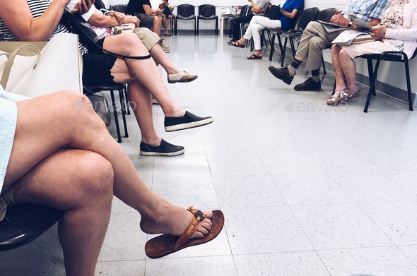 People sitting on chairs waiting their turn in a waiting room at a doctors office