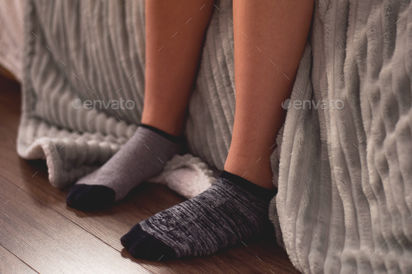 Teenage girl sitting on her bed wearing mismatched ankle socks