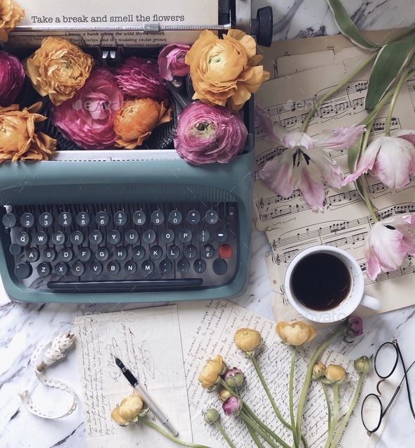 A desk with an old vintage antique typewriter with a phrase TAKE A BREAK AND SMELL THE FLOWERS