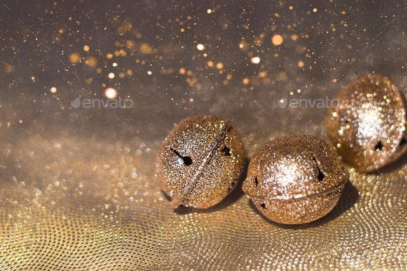 Golden jingle bells on sparkling glittery gold background with copy